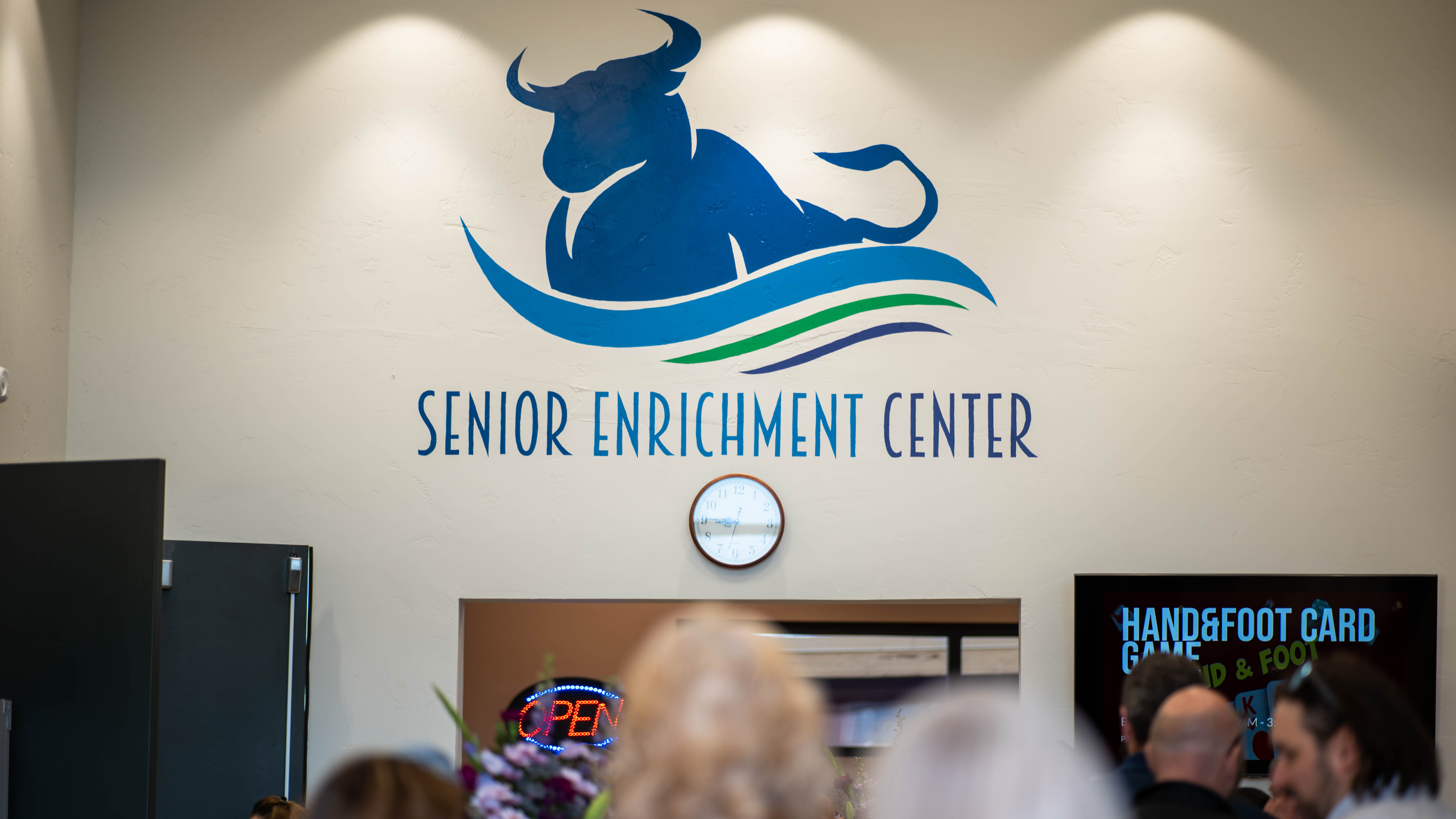 Painting of Blue silhouette Bull Logo and sign that reads "Senior Enrichment Center" on the inside back wall of the front entrance of the Senior Enrichment Center