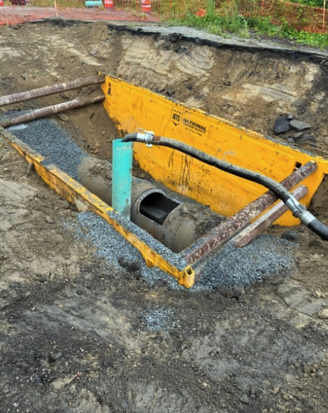 Large drainage ditch with piping and yellow metal box for filtering