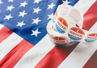 "roll of "I voted" stickers on top of an American flag"