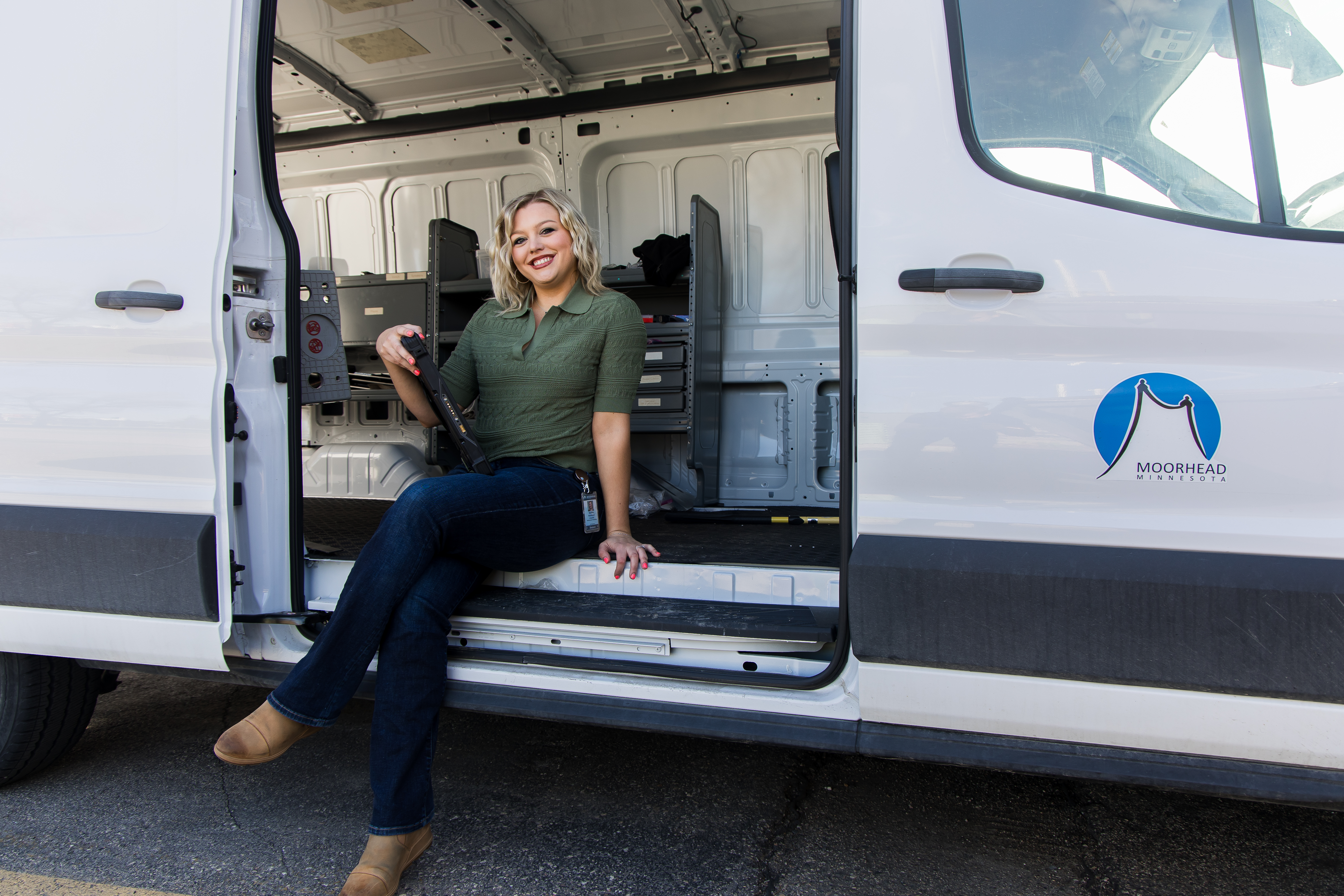 An IT employee sits in the IT Van holding a laptop
