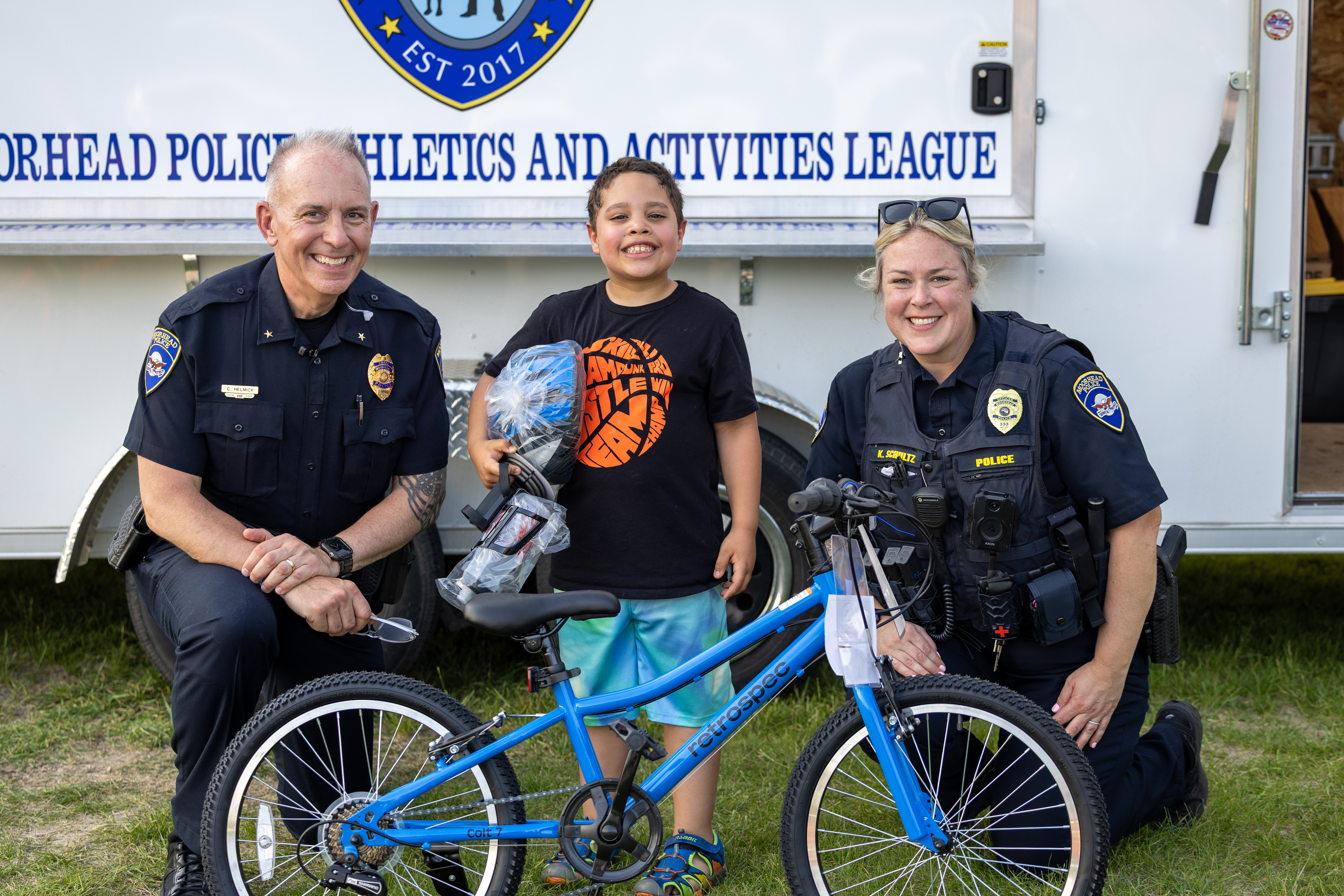 Officers pose with a kid who won a bike at Safe City Nights